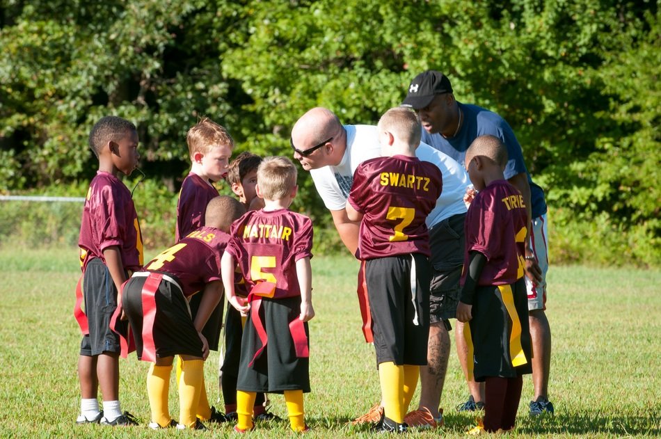 two coaches with child boyâs football team outdoor