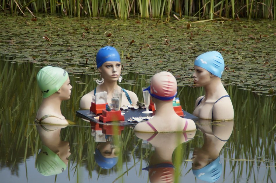 Women in swimming caps communicate in the pond