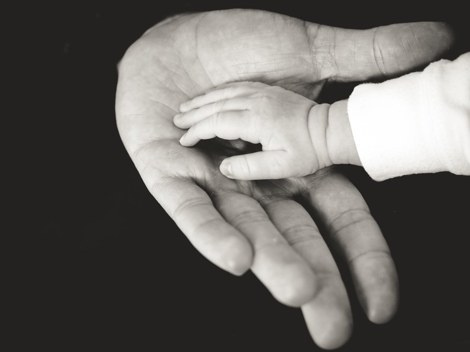 the palm of a small child on the palm of an old man
