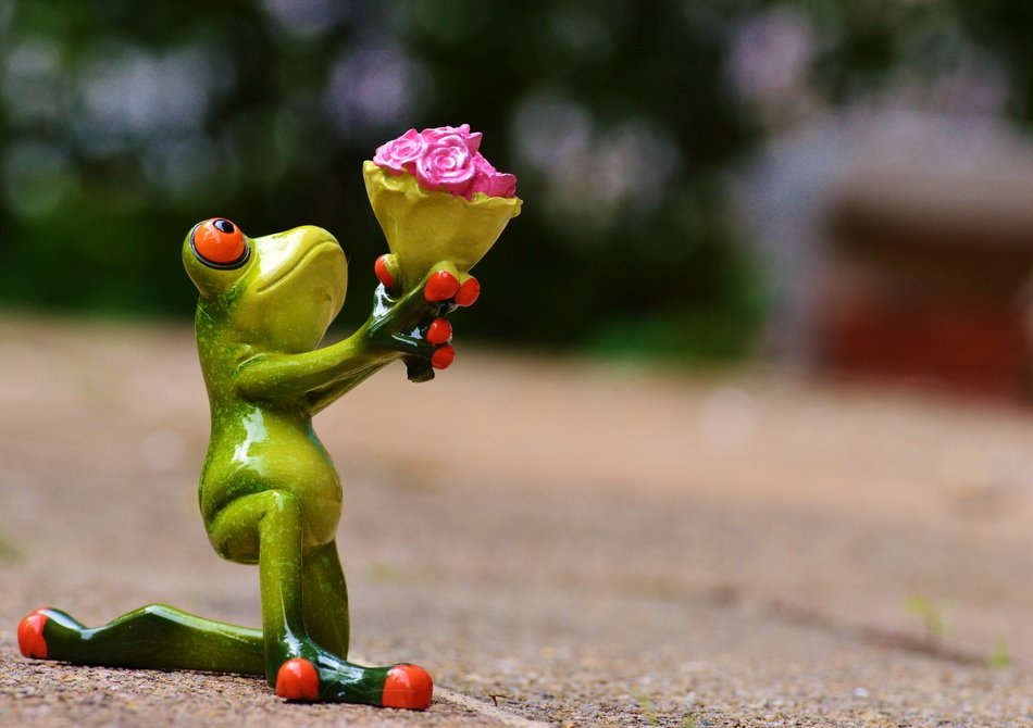 A figure of a green frog with a bouquet of flowers