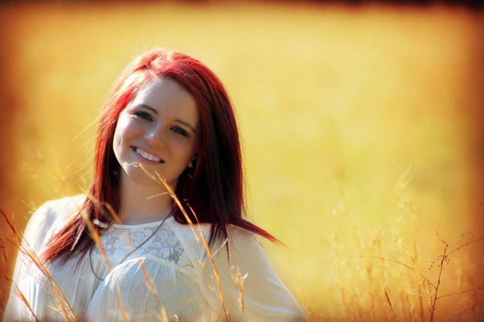 girl with red hair on a background of a yellow rural field