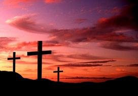 crosses on top of a mountain against a pink sky