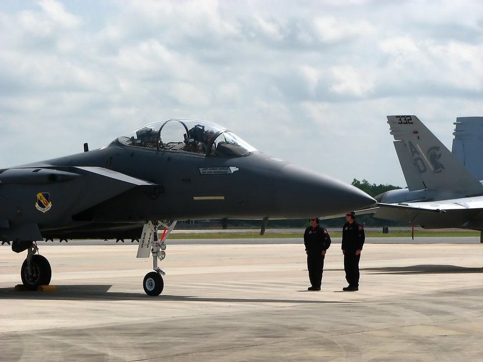people stand near a military plane
