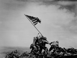 black and white photo soldiers carry the American flag during World War II