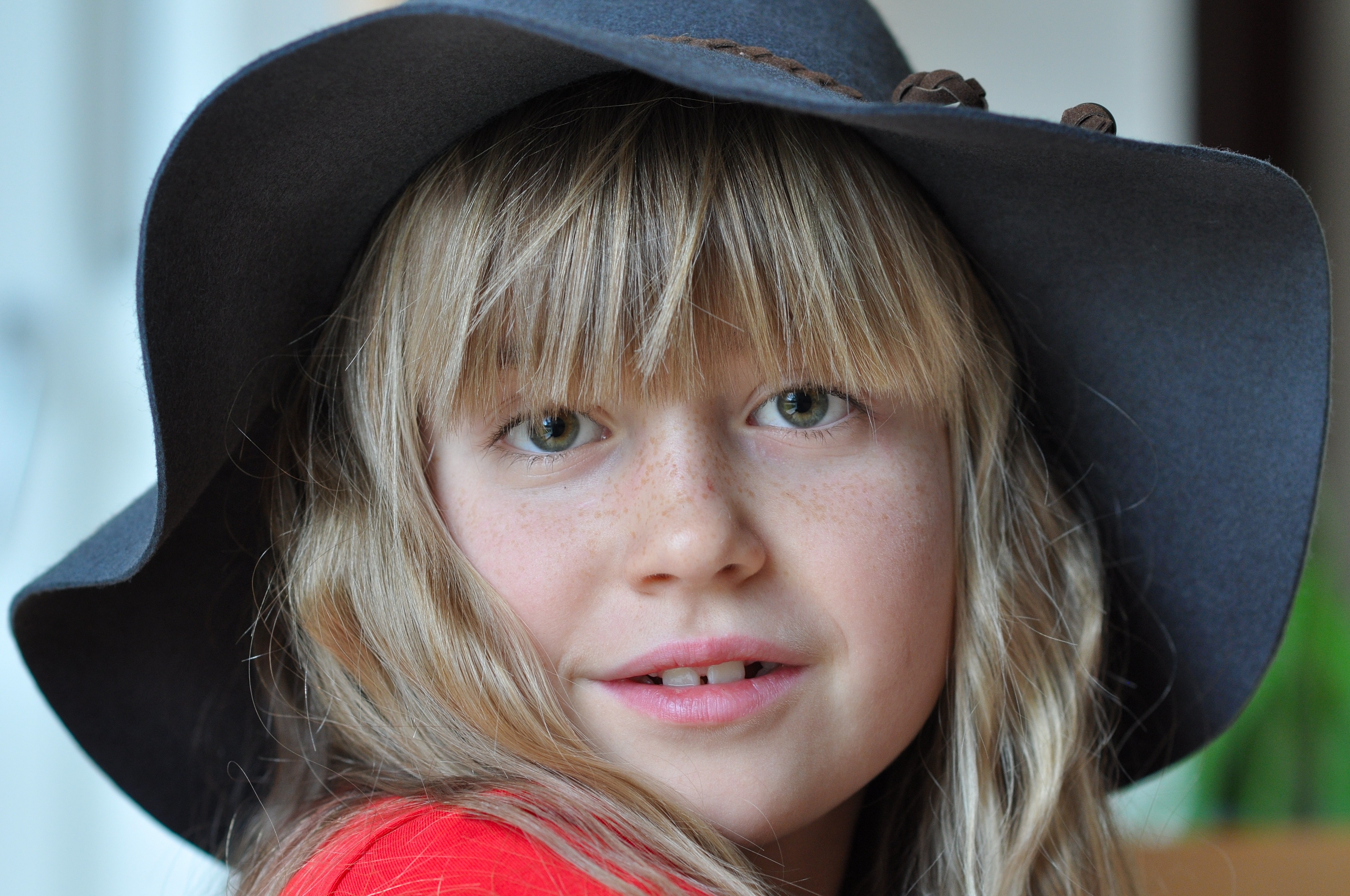 A little girl with long white  hair  in a hat with wide brim 