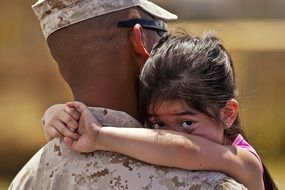 daughter hugs military dad by the neck
