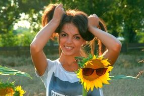 girl stands near a sunflower