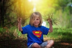 girl in a superman t-shirt with bundles of grass in her hands