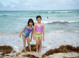 happy girls on sand in waves