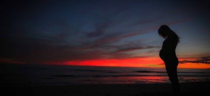 A pregnant woman on the see shore and sunset