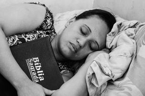 A slipping woman with the bible in the hands