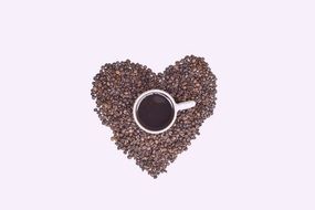 coffee cup standing on coffe beans in shape of heart