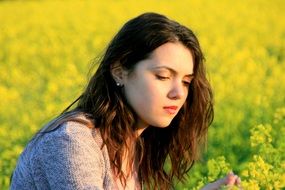 thoughtful girl among yellow flowers