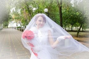 Bride with a pink bouquet with a length of white veil