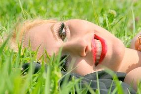 smile of girl with blond hair on a background of grass