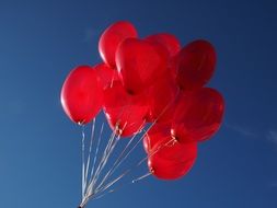 Connected red balloons against the sky background