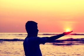 silhouette of a man at sunset holds the sun in his hands