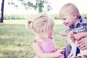 Girl and boy are playing with the kitten
