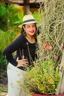 woman in a hat against the backdrop of greenery