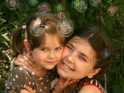 the sisters hugging on the background of soap bubbles