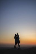 silhouette of a kissing couple in love at sunset