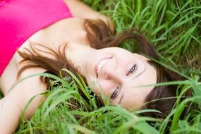 girl in a pink dress lies in the meadow
