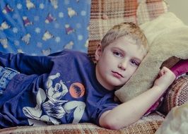 boy is resting on a plush pillow on a sofa