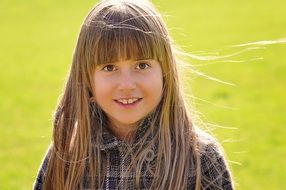 Little girl with long hair among the meadow