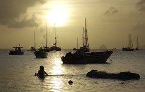 sunset seascape with boats and swimmer