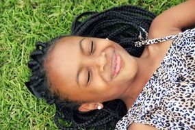 Smiling beautiful African girl laying on the grass