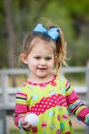happy girl with the bow playing among the plants
