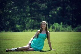 happy girl in turquoise dress on green grass