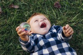 little boy in a plaid shirt plays with a ball