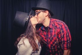 kiss of a couple in love in black hats