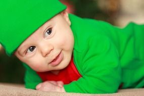 happy baby in a green Christmas costume