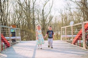 boy and girl go for hands on the bridge