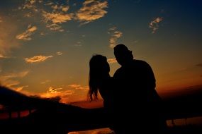 Loving couple outlines sunset bridge