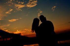 Silhouettes of two lovers against the sunset background