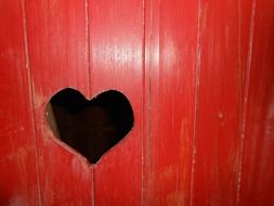 a hole in the red door in the shape of a heart