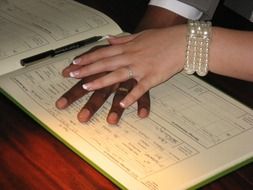 hands of the newlyweds on the registration journal