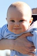 baby in blue jumpsuit on hand under the light