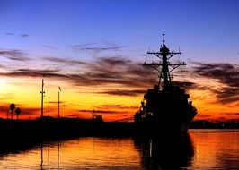 beautiful sunset sky above sea and navy ship at harbor, usa, california