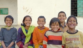 group of smiling asian children at building, india