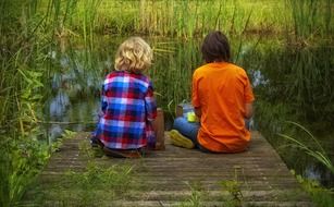 friends sitting on a lake bank