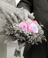 hands of the newlyweds on the wedding bouquet