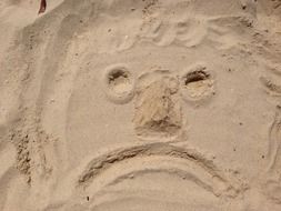 sad face sketch on sand