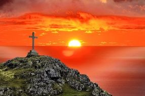 stone cross on hill, sunset at background