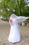 Bride with a long veil in the park