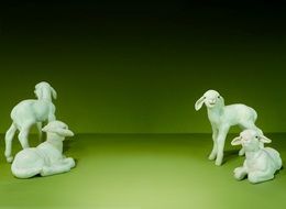 Four white figures of lambs on green surface