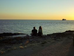 romantic couple is sitting on the beach